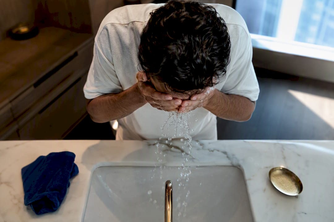 Man rinsing face during morning skincare routine